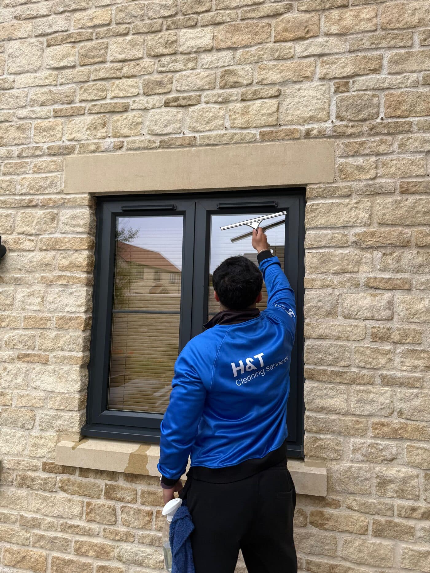 H&T technician cleaning a residential window